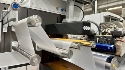 a complex industrial machine that is extruding transparent sheets of plastics across a series of rollers