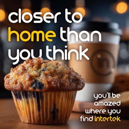 A muffin sitting on a table next to a paper coffee cup